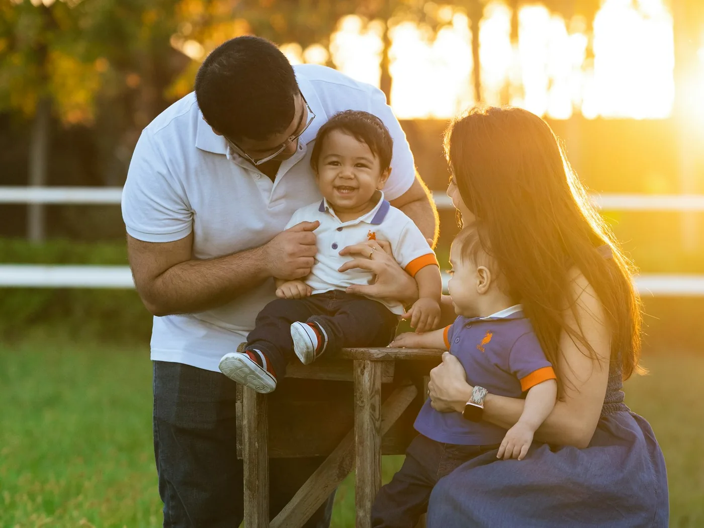 Una familia con dos niños pequeños comparte un momento al aire libre, al atardecer.